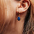 Colgante de oreja dorado con piedra ovalada azul en la oreja