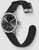 Smartwatch con correa de silicona negra, caja plateada, esfera negra y cierre de metal