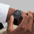 Smartwatch en la muñeca con esfera negra y correa negra