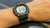 Reloj digital para hombre en la muñeca con correa negra y pantalla digital iluminada