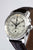 Reloj de hombre con cronógrafo, caja plateada, corona y pulsadores, correa de cuero marrón