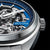 Pulsera de hombre con movimiento expuesto, esfera azul y caja de metal, vista lateral