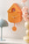 Orange Wanduhr im Häuschen-Design mit Uhrwerk und rundem Pendel