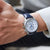 Pulsera de hombre en la muñeca: correa de cuero azul, caja plateada, esfera blanca