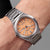 Pulsera de hombre en la muñeca con esfera naranja y correa de metal