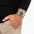 Reloj de hombre en la muñeca con esfera verde y pulsera de metal plateado