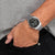 Reloj de hombre en la muñeca con esfera negra y pulsera de acero inoxidable plateado