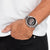 Reloj de pulsera con cronógrafo: correa de acero inoxidable y esfera negra en la muñeca.