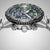 Detalle de reloj de pulsera para hombre: bisel estriado, esfera verde y subesferas de cronógrafo