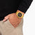 Reloj de hombre en la muñeca con pulsera de acero inoxidable en tono dorado y esfera negra