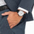 Reloj de hombre en la muñeca con correa de cuero negra y esfera clara