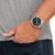 Reloj de hombre con esfera negra en la muñeca, pulsera de metal plateado