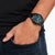 Reloj de hombre en la muñeca con correa negra y esfera verde