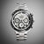 Reloj de hombre con correa de metal plateado, esfera plateada y múltiples subesferas de cronógrafo.