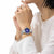 Reloj de mujer en la muñeca con esfera redonda azul y correa de acero inoxidable