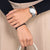 Reloj de mujer en la muñeca con correa de metal plateado y esfera blanca.