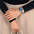 Reloj de mujer con esfera azul en la muñeca, correa de metal plateado