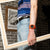 Casio G-Shock Uhr am Handgelenk an Jeans, orangefarbenes Armband