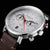 Reloj de hombre de frente, primer plano: esfera blanca, correa de cuero marrón, detalles rojos, cronógrafo