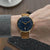 Reloj de hombre en la muñeca: esfera azul, caja dorada, correa de cuero beige