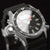 Reloj de hombre en detalle: esfera negra con marcadores verdes y bisel de buceo
