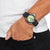 Pulsera de hombre en la muñeca con correa de caucho negra y esfera amarilla