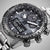 Reloj de hombre primer plano: esfera negra con subesferas de cronógrafo e índices luminosos