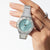 "Reloj de mujer en la muñeca con esfera azul claro y pulsera de acero inoxidable plateado"