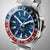 Reloj de pulsera para hombre de acero inoxidable en vista angular: esfera azul, bisel GMT rojo/azul y corona