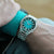 Reloj de hombre en la muñeca con esfera verde y pulsera de acero inoxidable plateado
