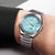 Reloj de hombre con esfera turquesa y correa de titanio en la muñeca