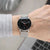 Reloj de hombre con esfera negra y brazalete de metal plateado, vista lateral