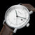 Reloj de hombre primer plano: esfera blanca con detalles verdes y correa de cuero marrón