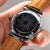 Reloj de hombre con esfera oscura, correa de cuero marrón y caja plateada