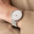 Reloj de mujer de lado en la muñeca con esfera blanca y correa de malla