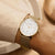 "Reloj de mujer en la muñeca: esfera blanca y pulsera de malla dorada"
