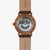Reloj de hombre, parte trasera: movimiento visible, correa de cuero marrón, fondo de caja color bronce.