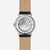 Reloj de hombre con tapa trasera abierta y movimiento visible, correa de cuero beige.