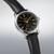 Reloj de hombre, vista lateral con esfera negra y correa de cuero marrón
