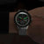 Reloj de hombre con correa de metal, esfera oscura y detalles verdes
