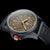 Reloj deportivo con esfera beige, caja oscura y corona naranja