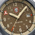 Detalle de la esfera de un reloj deportivo: pantalla beige, manecillas plateadas, ventana de fecha a las 31
