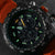 Esfera de reloj de pulsera para hombre en detalle con marcadores luminosos verdes y subesferas de cronógrafo