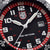 Primer plano de la esfera de un reloj deportivo: anillo de bisel rojo, manecillas blancas, ventana de fecha a las 3 en punto