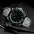 Reloj de hombre con esfera negra, caja plateada y correa de cuero negra.