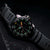 Pulsera de hombre con esfera negra, segundero rojo e índices luminiscentes verdes.