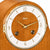 Reloj de mesa de madera primer plano: esfera redonda con números arábigos, manecillas doradas.