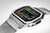 Reloj digital con caja plateada, pantalla LCD con retroiluminación verde y correa de malla