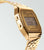 Reloj Casio Vintage dorado con correa de metal, caja lateral y pantalla LCD con alarma.