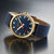 Reloj Mondaine con esfera azul, caja dorada y correa textil azul